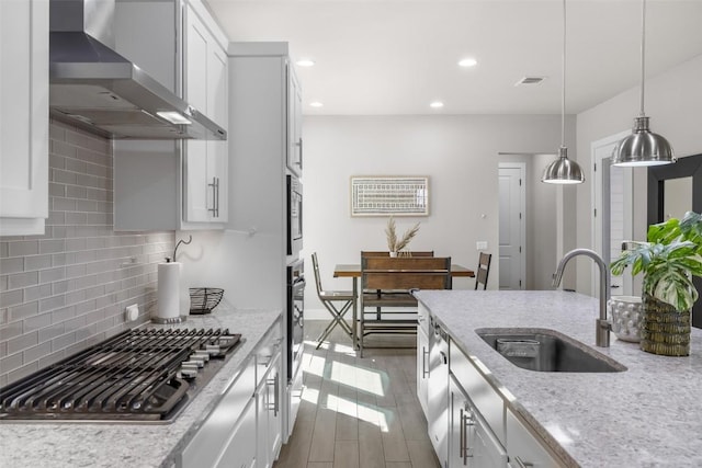 2505 Moreno St, Austin, TX 78723 - kitchen featuring wall chimney range hood, stainless steel appliances, a sink, backsplash, and white cabinets