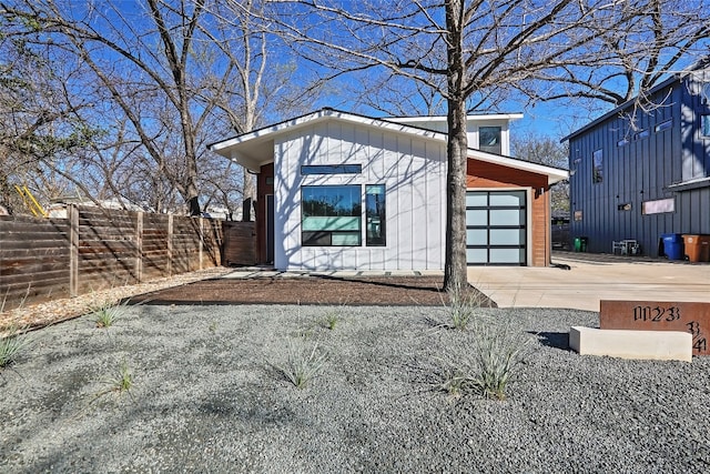 view of outdoor structure featuring an attached garage, fence, and driveway