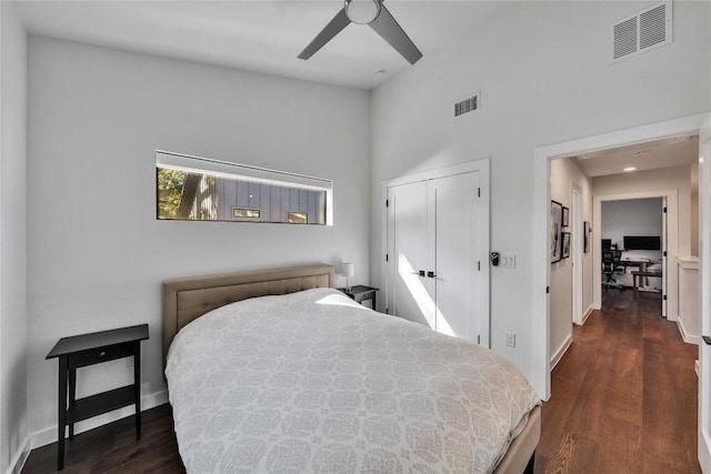 bedroom with dark wood finished floors, baseboards, visible vents, and a closet