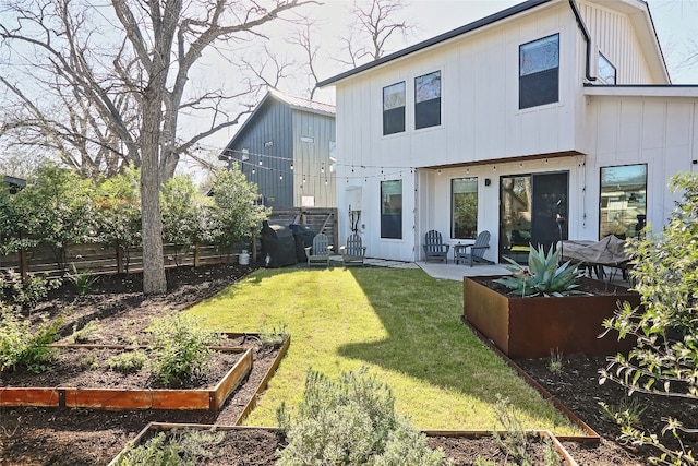 back of property with fence, a vegetable garden, a yard, a patio area, and board and batten siding