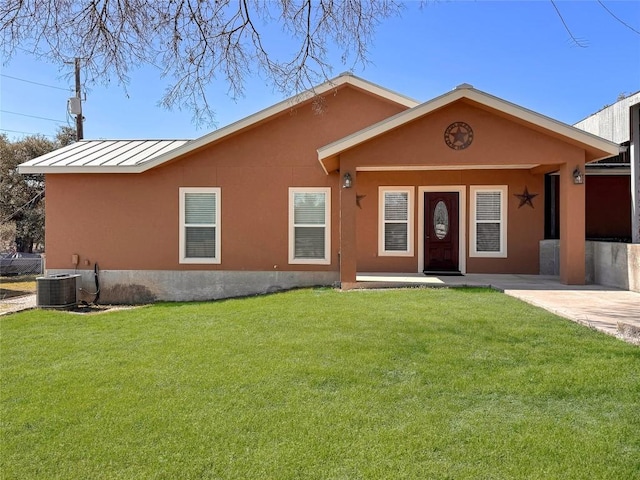 ranch-style home with stucco siding, a front yard, and a standing seam roof