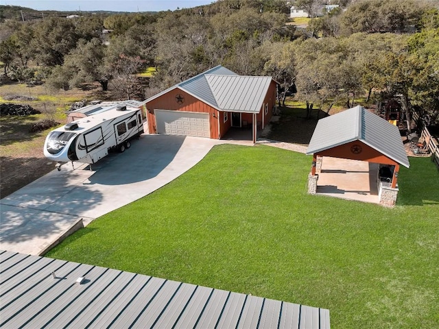 view of front facade featuring a front yard, a wooded view, driveway, a standing seam roof, and metal roof