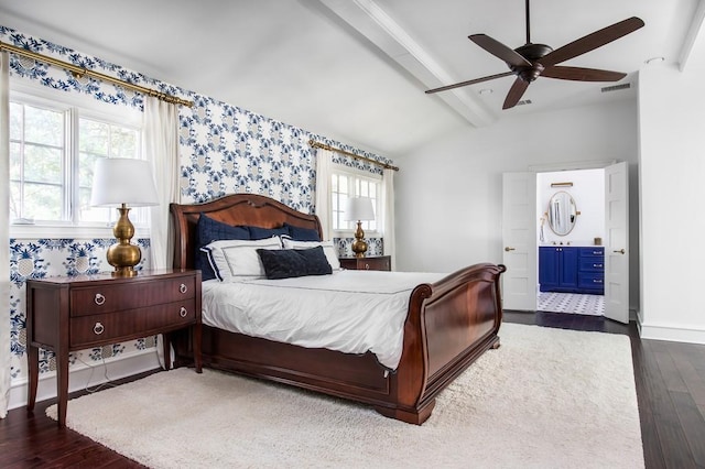 bedroom featuring wood finished floors, baseboards, wallpapered walls, lofted ceiling with beams, and ensuite bathroom