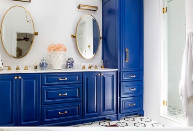 bathroom featuring double vanity, a shower, and a sink