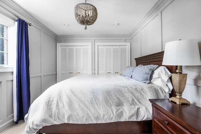 bedroom featuring two closets, ornamental molding, and a decorative wall