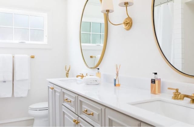 bathroom featuring double vanity, toilet, a shower with shower curtain, and a sink