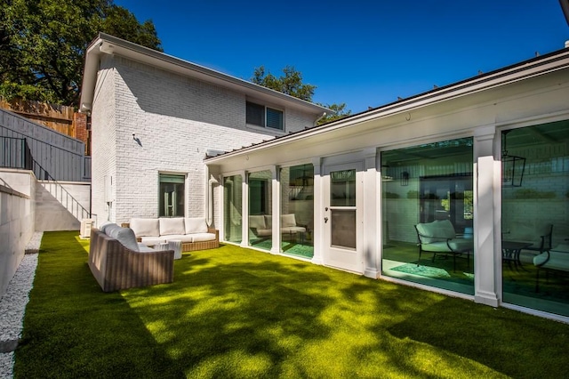 back of property with an outdoor living space, brick siding, a lawn, and fence