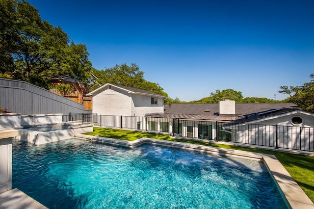 view of swimming pool with fence and a pool with connected hot tub