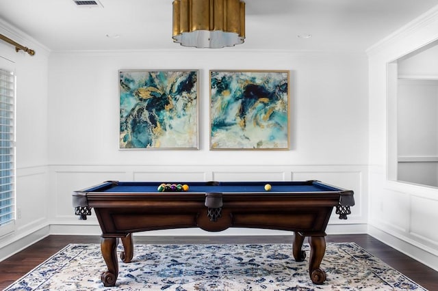 game room with a decorative wall, visible vents, dark wood-type flooring, and ornamental molding