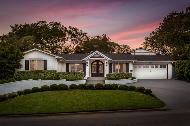 single story home with french doors, an attached garage, concrete driveway, and a front lawn