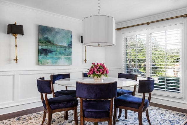 dining room featuring wainscoting, dark wood-style flooring, crown molding, and a decorative wall