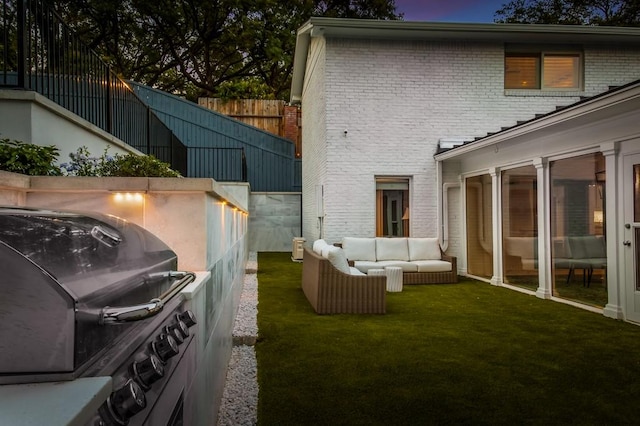 view of side of home featuring a yard, fence, brick siding, and an outdoor hangout area