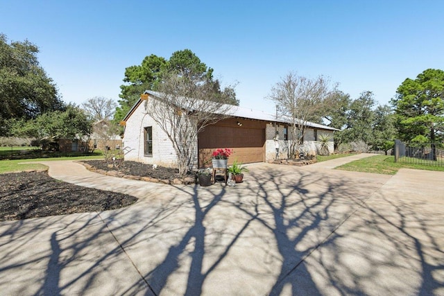 exterior space featuring concrete driveway, an attached garage, and fence