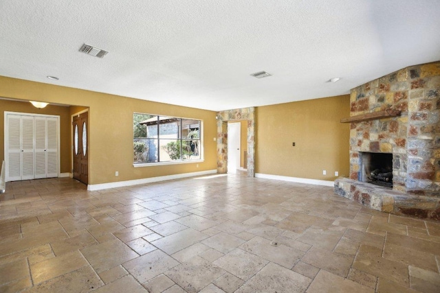 unfurnished living room featuring stone tile floors, visible vents, a stone fireplace, and baseboards