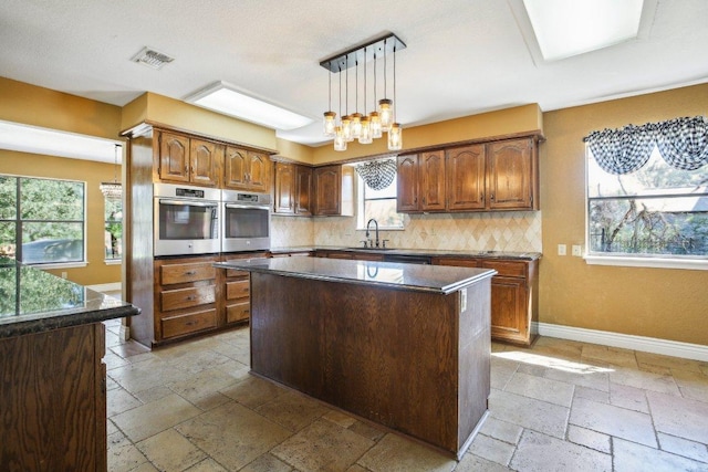 kitchen with stainless steel oven, visible vents, and stone tile flooring