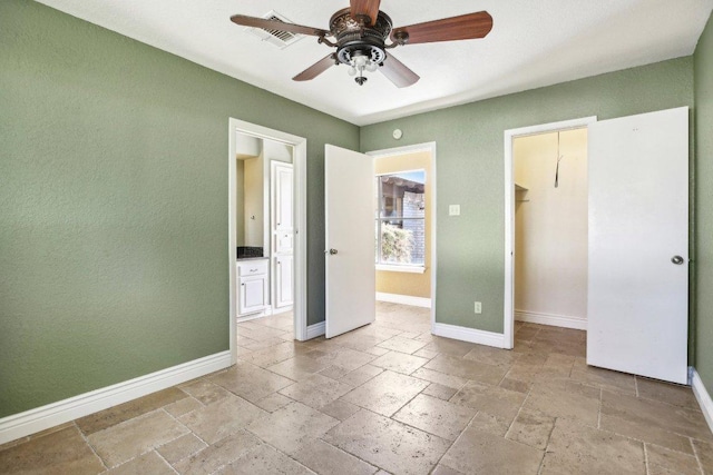 unfurnished bedroom featuring stone tile floors, a spacious closet, visible vents, and baseboards