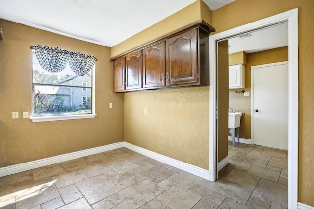 clothes washing area featuring visible vents, baseboards, and stone tile flooring