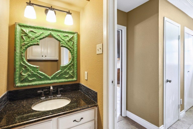 bathroom featuring tile patterned floors, vanity, baseboards, and a textured wall