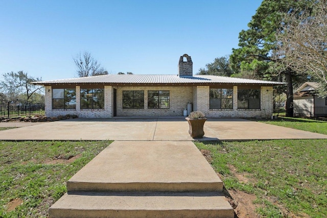 view of front of property with brick siding, a patio area, a chimney, and a front lawn