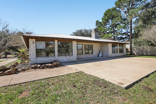 rear view of property featuring a patio, brick siding, and a chimney