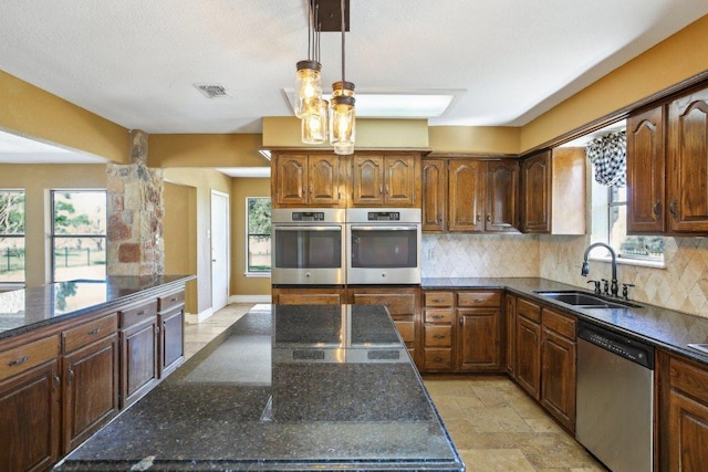 kitchen featuring visible vents, stone tile floors, decorative backsplash, stainless steel appliances, and a sink