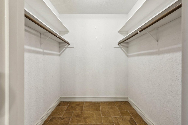 walk in closet featuring stone tile floors