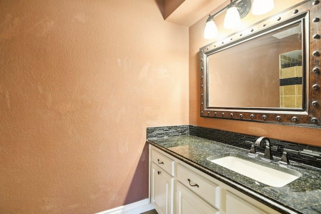 bathroom with vanity, a textured wall, and baseboards