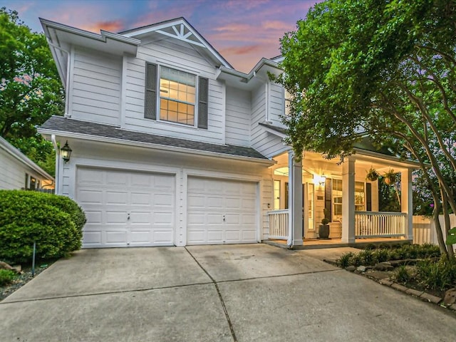 view of front of home featuring an attached garage, covered porch, driveway, and a shingled roof