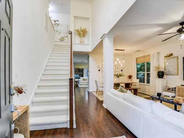 entryway featuring stairway, wood finished floors, decorative columns, ornamental molding, and ceiling fan