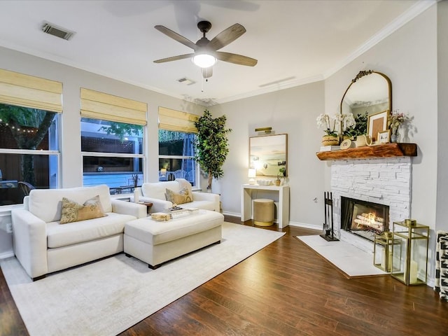 living area featuring visible vents, a stone fireplace, wood finished floors, and ornamental molding