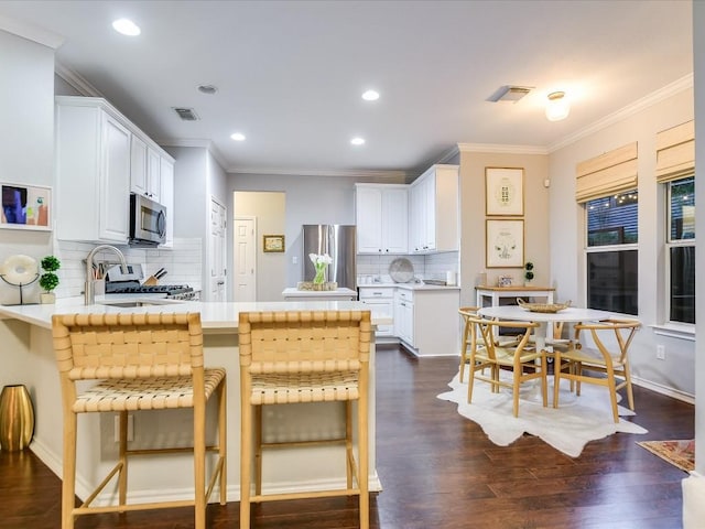 kitchen with dark wood finished floors, appliances with stainless steel finishes, white cabinets, a peninsula, and light countertops