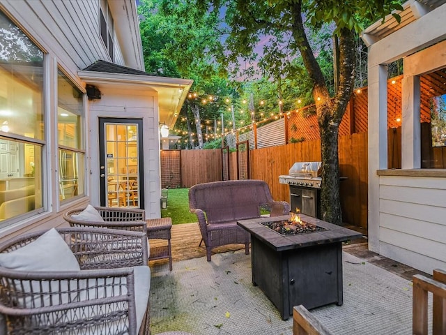 view of patio featuring an outdoor living space with a fire pit, fence, and grilling area