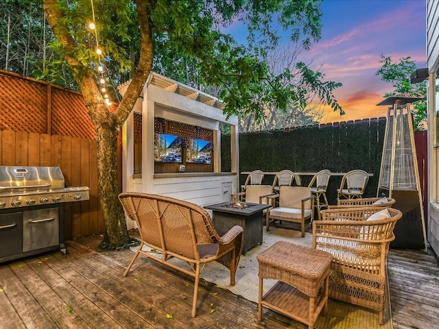 patio terrace at dusk with a deck, a fire pit, and a grill