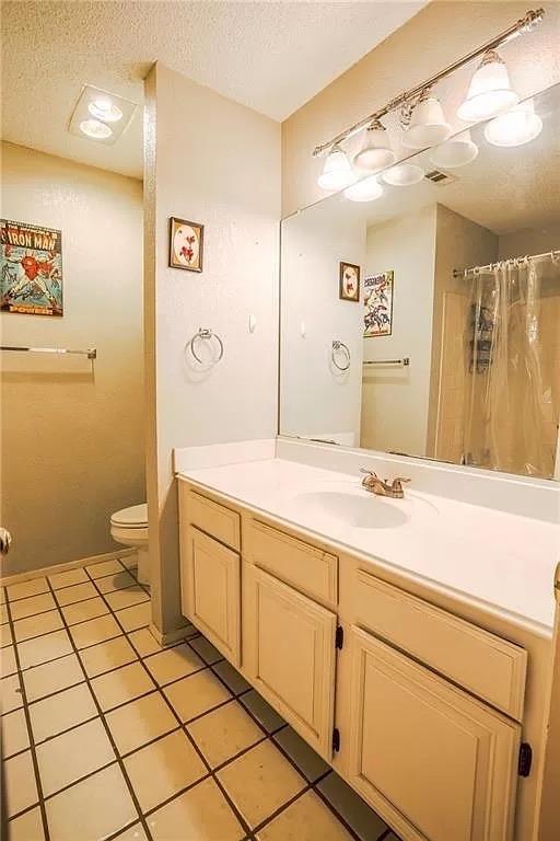 full bath featuring curtained shower, a textured ceiling, toilet, and vanity