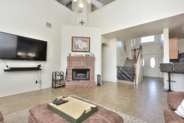 living room with stairway, visible vents, a high ceiling, a fireplace, and tile patterned flooring