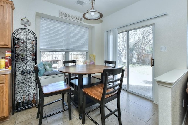 dining space featuring light tile patterned floors, a healthy amount of sunlight, and visible vents