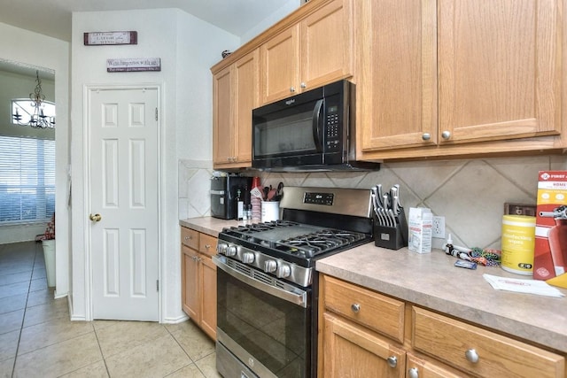 kitchen with stainless steel range with gas cooktop, light tile patterned flooring, black microwave, light countertops, and decorative backsplash