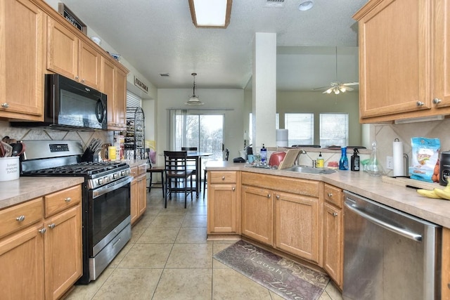 kitchen featuring a sink, appliances with stainless steel finishes, a peninsula, light tile patterned floors, and decorative backsplash