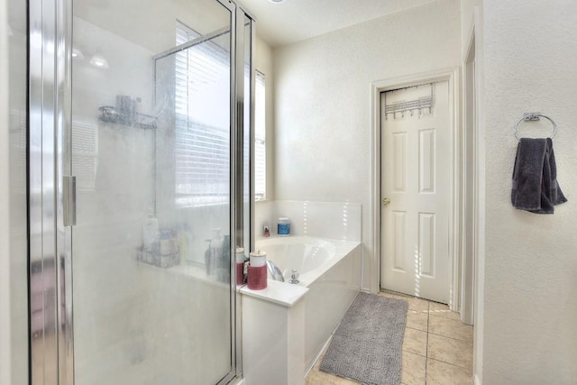 full bathroom featuring a stall shower, a textured wall, a bath, and tile patterned flooring