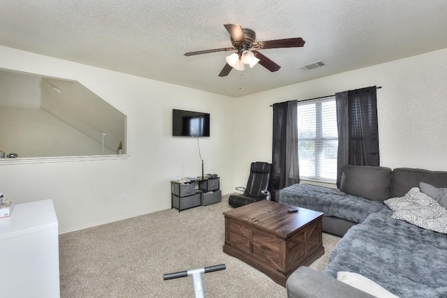 living area featuring carpet flooring, a ceiling fan, visible vents, and a textured ceiling