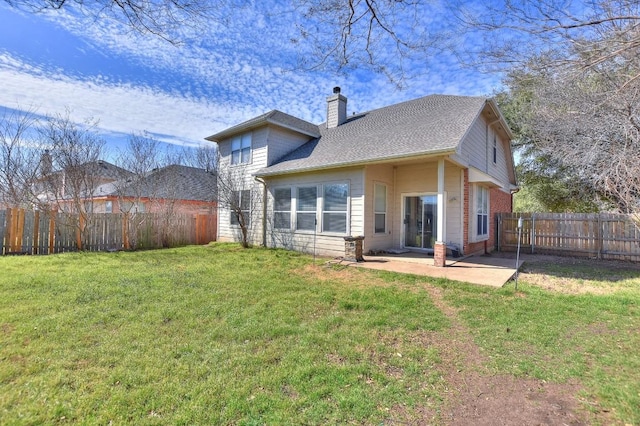 back of property featuring a patio, a yard, a fenced backyard, a chimney, and brick siding