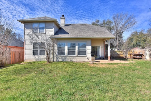 rear view of property featuring roof with shingles, a chimney, a fenced backyard, a yard, and a patio