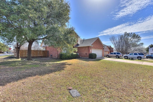 view of side of home with brick siding, an attached garage, fence, a lawn, and driveway