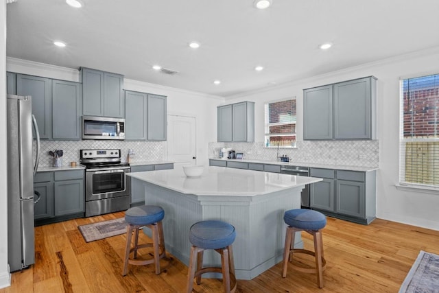 kitchen with stainless steel appliances, a kitchen bar, a kitchen island, and ornamental molding