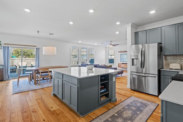 kitchen featuring a kitchen island, light wood-type flooring, gray cabinetry, stainless steel fridge, and backsplash