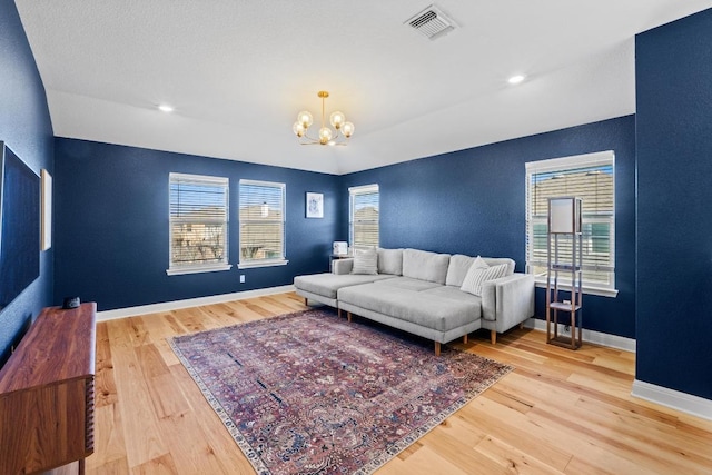 living area featuring visible vents, baseboards, hardwood / wood-style floors, recessed lighting, and a notable chandelier