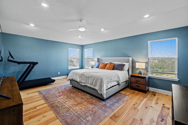 bedroom featuring multiple windows, baseboards, and light wood finished floors