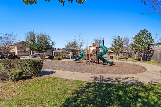 communal playground featuring a lawn and fence