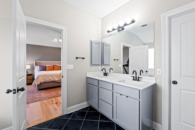 ensuite bathroom featuring tile patterned flooring, double vanity, visible vents, and a sink