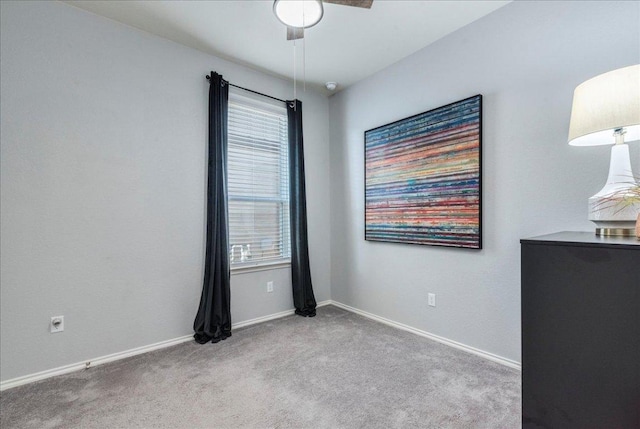 carpeted spare room featuring baseboards, a healthy amount of sunlight, and a ceiling fan